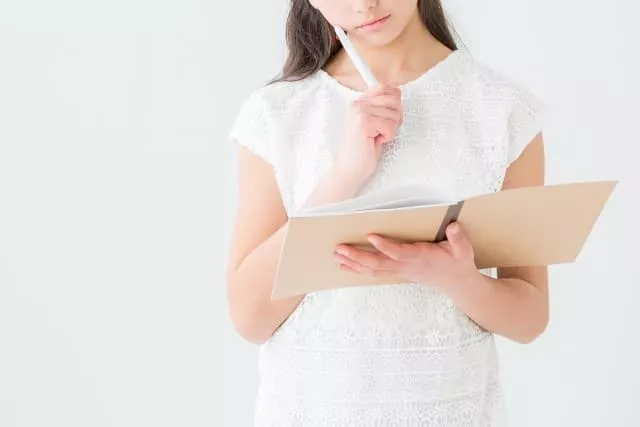 ノートを見ながら考える女性