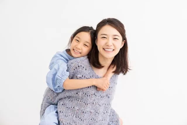 子供をおんぶしながら笑う女性